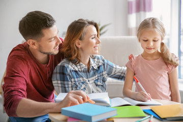 Little girl with parents doing homework at home