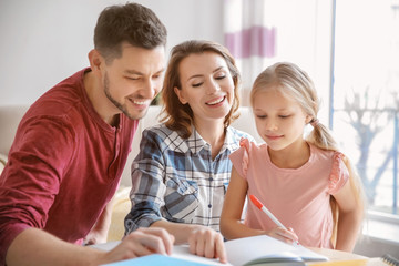 Little girl with parents doing homework at home