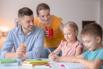 Little children with parents doing homework at home