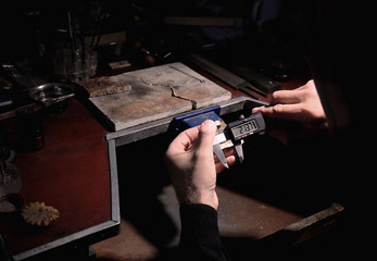 Jeweler measuring golden ring with digital caliper, closeup