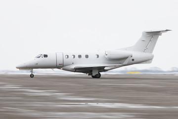 Side view of small Private business Jet taxing on runway for take off, in moving, winter time. Business, private aviation concept