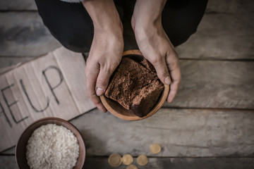 Poor woman holding bowl with bread, closeup