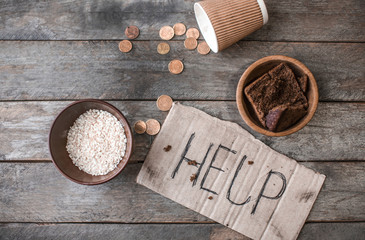 Piece of cardboard with word HELP and food on wooden background. Poverty concept