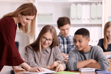 Fototapeta premium Group of teenagers doing homework with teacher in classroom