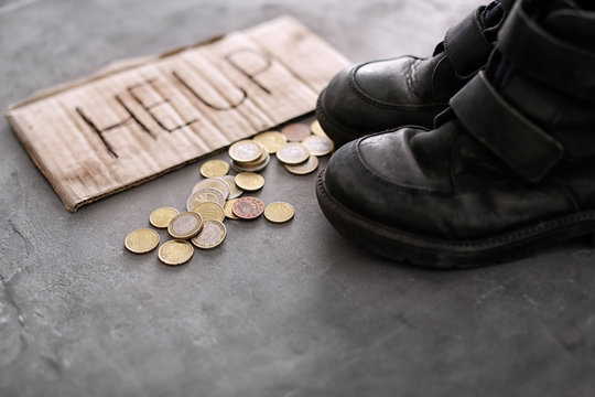 Old shoes, coins and piece of cardboard with word HELP on grey background. Poverty concept