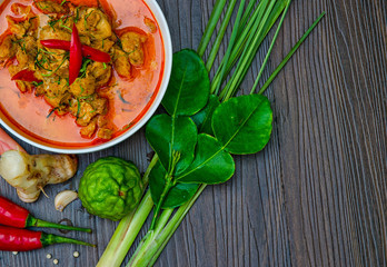 Chicken panang curry in the white bowl and fresh spice on brown wooden background Thai food