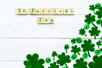 Happy St Patricks Day message and a lot of green paper clover leaf on white wooden background