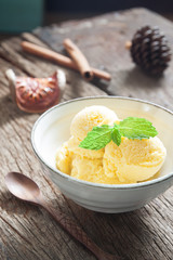 Homemade mango ice cream with mint in ceramic bowl on rustic wooden table, Food and lifestyle concept