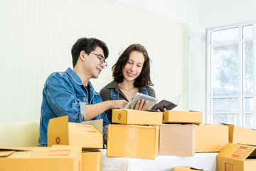 Worker In Warehouse Checking Box Using Digital Tablet.Start up small business entrepreneur SME or freelance man and woman working  at home concept, Young Asian small business owner, online marketing.