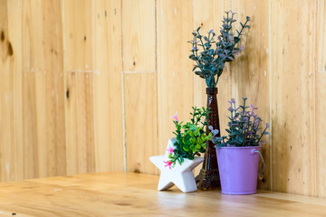 Small plastic potted plants in the color pot on wooden table
