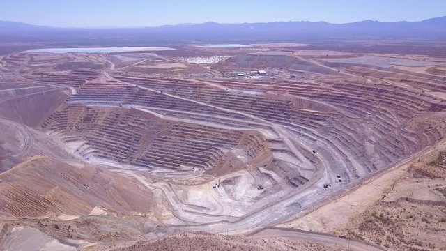 An aerial over a vast open pit strip mine in the Arizona desert.