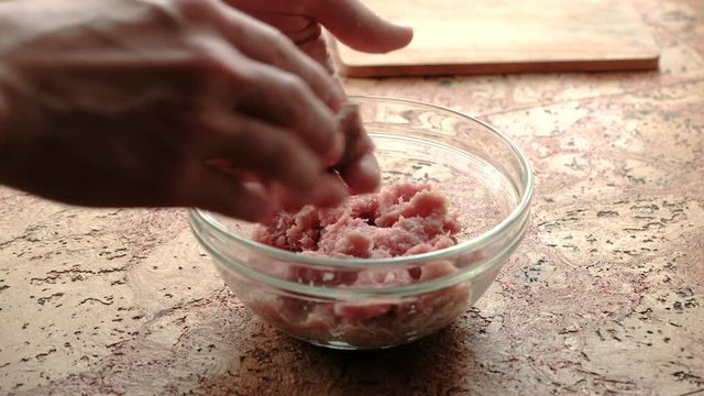 Close-up of man's hands make cutlets of minced meat. Transparent plate on the kitchen table.