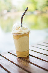 ice coffee frappe on glass table with nature background. subject is blurred.