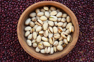 Fototapeta premium pistachios in wooden bowl on red bean background