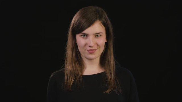 A beautiful young lady showing a shhh meme against a black background. Medium Shot