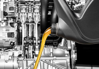 Pouring oil lubricant motor car from bottle on engine background