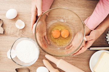 Cooking cupcakes in kitchen. Female and children's hands hold bowl with eggs.