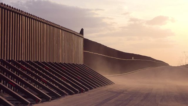 Dust blows at sunset at the border wall at the US Mexico border near Imperial sand dunes, California.