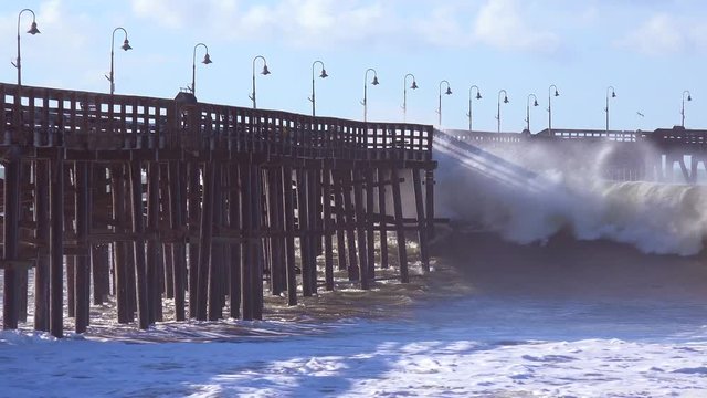 Huge waves crash on a California beach and pier during a very large storm event.
