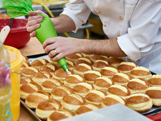 Confectioner is preparing bun with cream