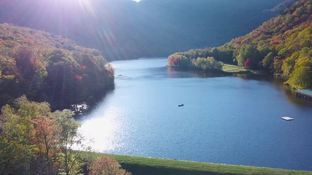Aerial over canoe on lake surrounded by vast forests of fall foliage and color in Maine or New England.