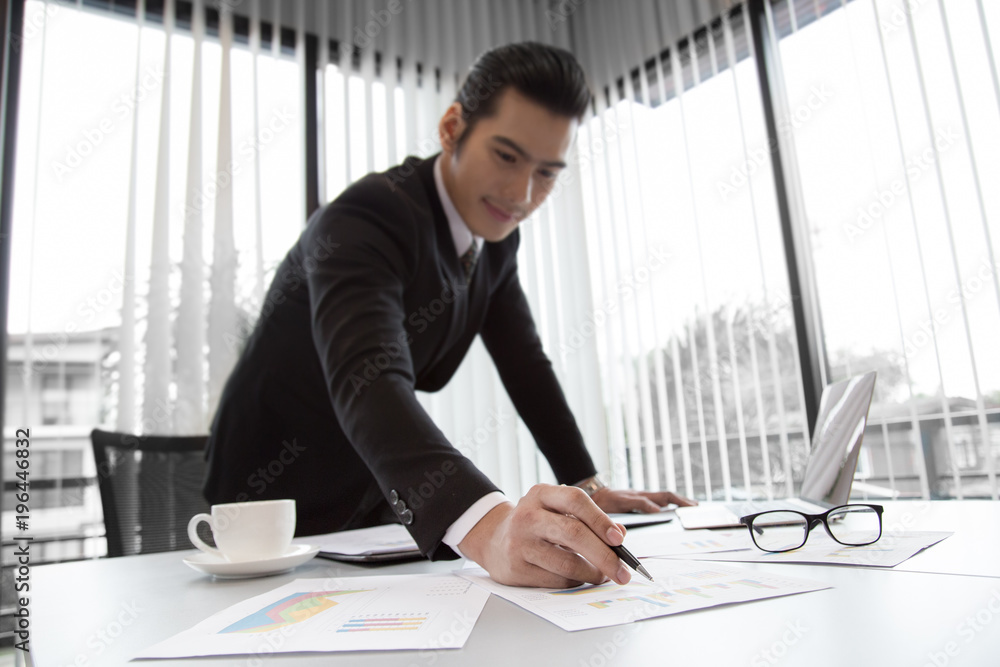 Wall mural young businessman checking business plan in document on desk in office