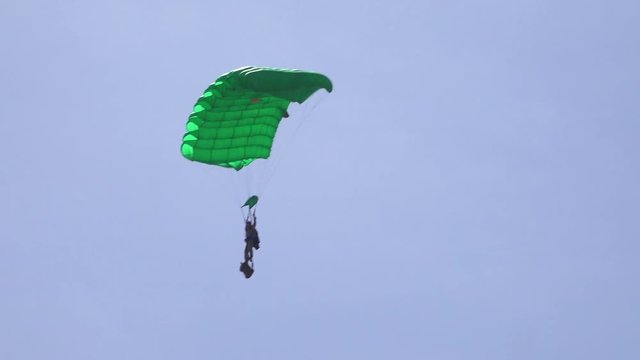 Elite military forces and paratroopers skydive onto and land in a field during training operations.