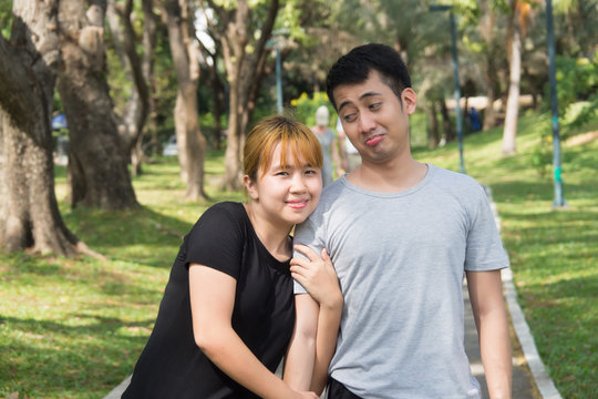 Young Asian love couple relax after an excercise in the park by playing to each other with emotion of love in warm afternoon. Young couple give a sense of love in the park. Couple outdoor excercise.