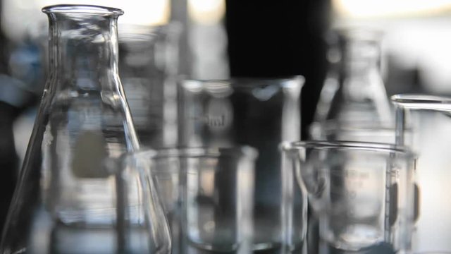 Scientific glass beakers coming into focus.