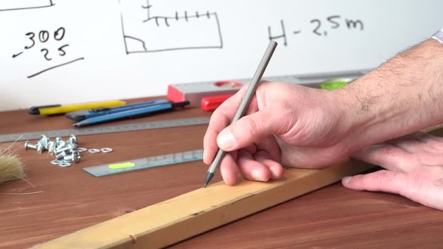 Drawing a pencil mark is a tool. The workbench wizard. Hand body part. Close up. Wooden table. 4K video