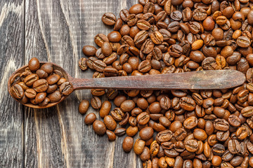 A coffee cup with coffee beans on an old wooden table. Fried coffee beans on a wooden background. Viewing from above.