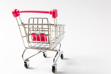 Close up of supermarket grocery push cart for shopping with black wheels and pink plastic elements on handle isolated on white background. Concept of shopping. Copy space for advertisement