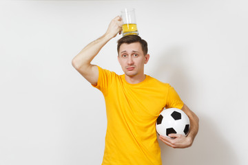 Inspired young fun upset European man, fan or player in yellow uniform hold on head pint mug of beer, soccer ball cheer favorite football team isolated on white background. Sport, lifestyle concept.