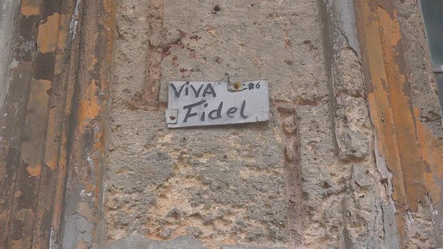 Old decaying windows on a building in Havana, Cuba with a sign saying Viva Fidel..