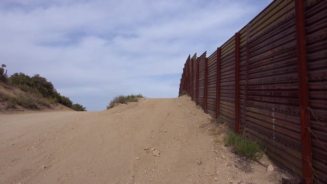 Slow pan of the U.S. Mexico border wall fence which ends suddenly in the desert of California.