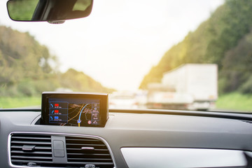 Satellite navigation system device in car with blurred transportation on highway road in Europe.