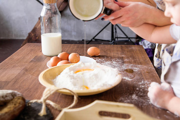 Mom and daughter are cooked together from flour, eggs and milk