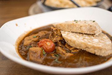 Traditional Goulash with knedle in a white bowl of beef stew on the wooden table, Germany menu