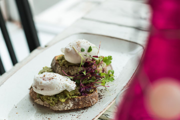 Avocado with poached eggs on toast in trendy hipster restaurant high end
