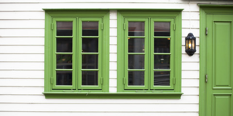 Casa blanca de madera con puerta y ventana verdes