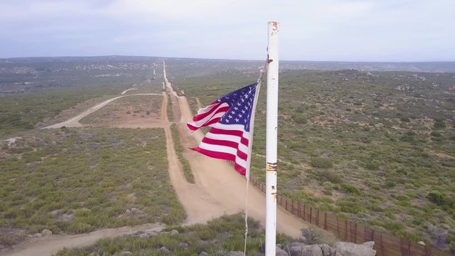 The American flag flies over the U.S. Mexico border wall in the California desert.