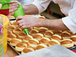 Confectioner is preparing bun with cream