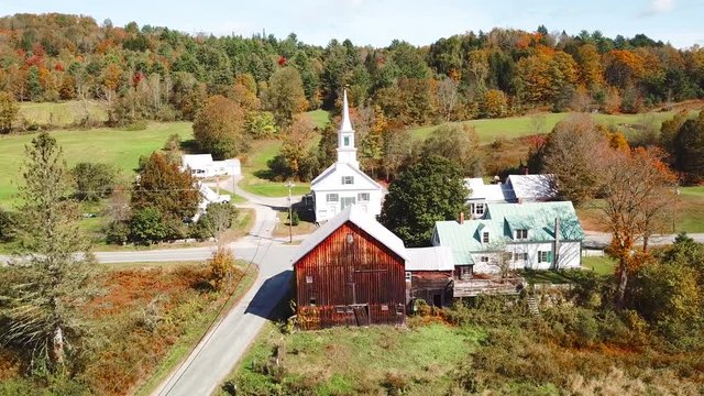 An aerial over a charming small village scene in Vermont with church, road and farm.