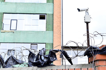 Camera video surveillance on the building background mounted on a brick wall, fenced with barbed wire.