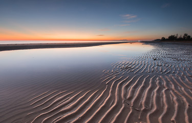 Fototapeta na wymiar Long expose seascape with stunning sunset colors and natural sand pattern. 