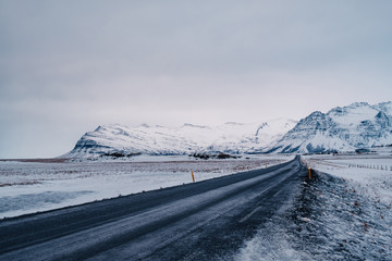 Beautiful View and winter landscape of Iceland's golden circle road during the sunset with the snow-capped mountain as a background and the road asphalt as a foreground.