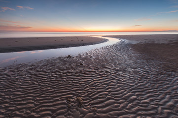 Fototapeta premium Long expose seascape with stunning sunset colors and natural sand pattern. 