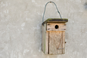 a wooden bird house hanging on a cement wall