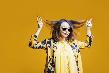 Young beautiful brunette woman with make-up fun and fashion in Studio on yellow background