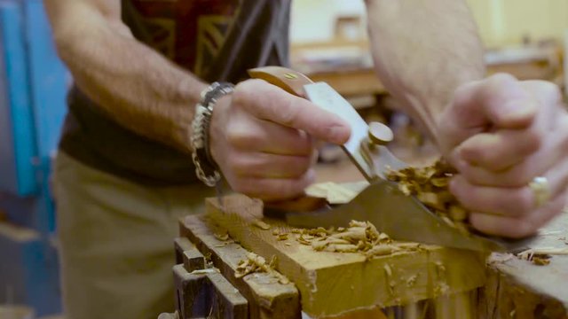 A woodworker works cutting wood in his studio.